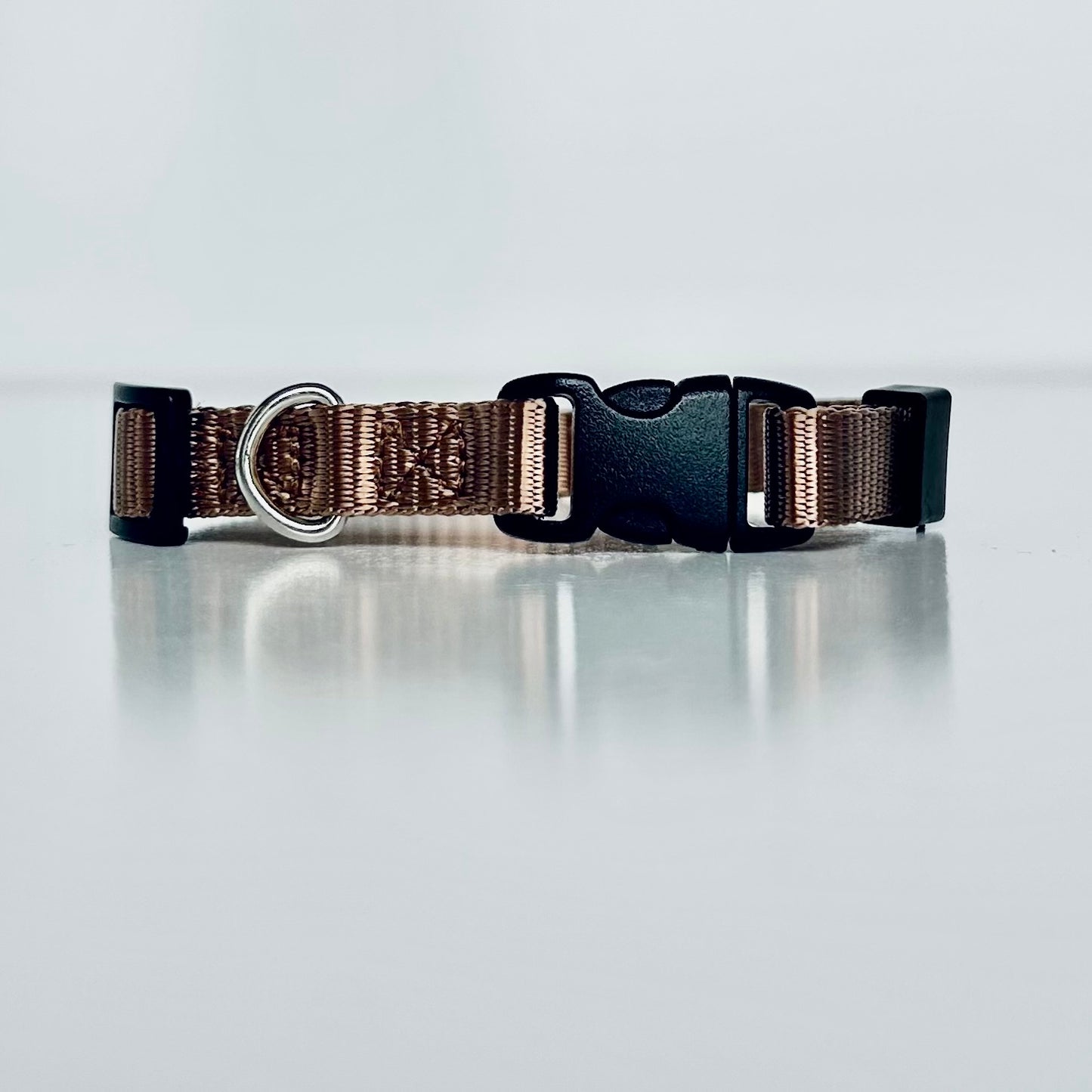 Bronze brown dog collar with a black buckle on a light grey background